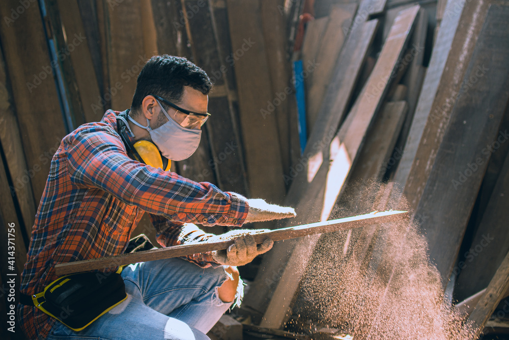 carpenter is working in a woodworking office.A white male carpenter is selecting the wood material and brushing off the sawdust. carpenter is working in a woodworking office.A white male carpenter is selecting the wood material and brushing off the sawdust.