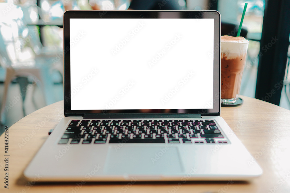 Fototapeta premium Laptop with Mock up blank screen on wooden table in front of cafe space for text. product display montage- technology concept.
