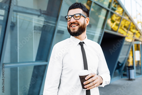 business man with laptop holding coffee in hand near office