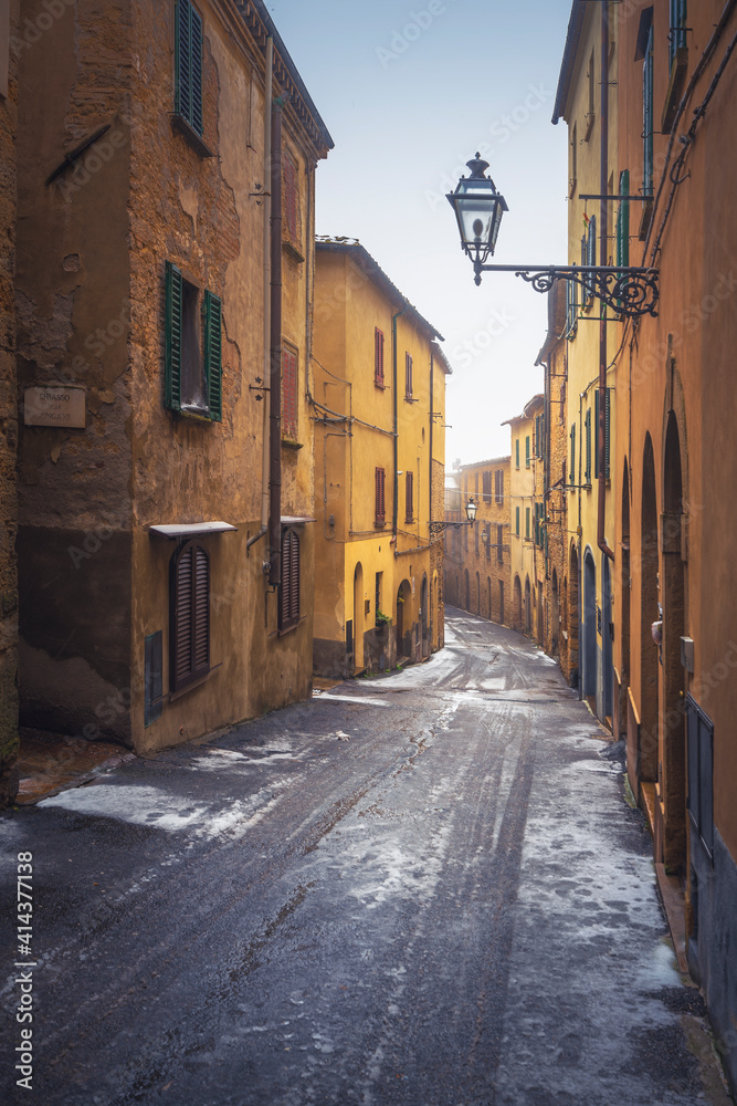 Volterra old town street during a snowfall in winter. Tuscany, Italy