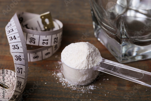 White protein powder in spoon and measuring tape
