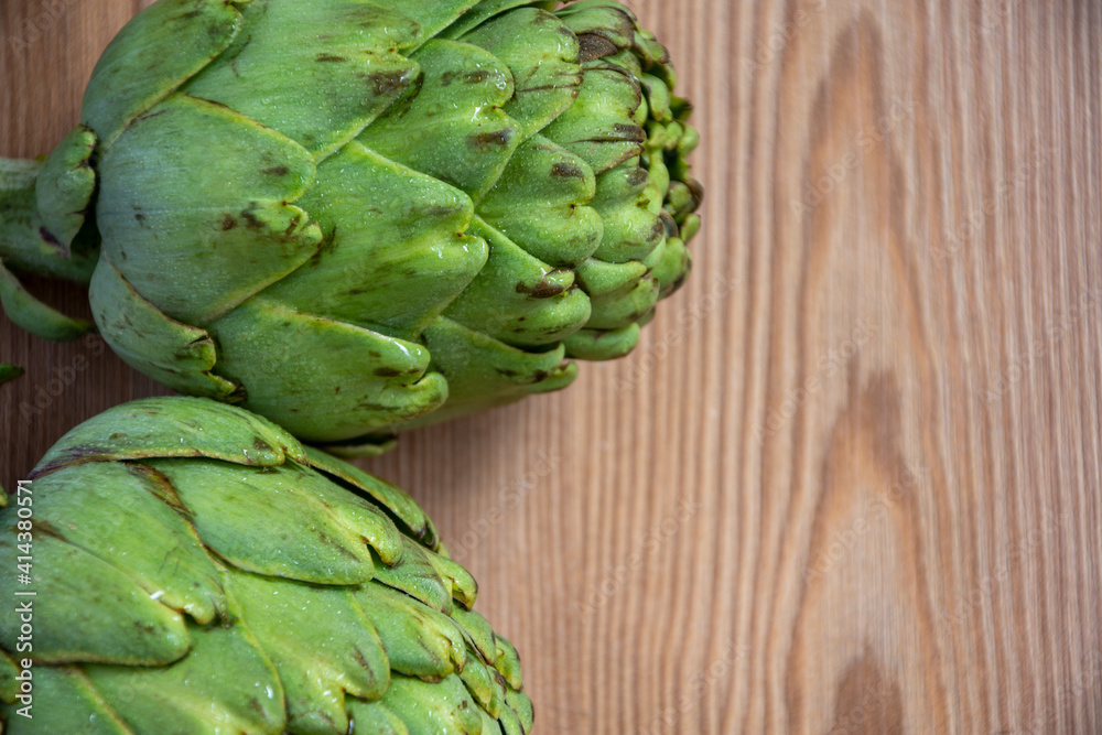 Aerial view of two green artichokes, on rustic wooden table, horizontally, with copy space Aerial view of two green artichokes, on rustic wooden table, horizontally, with copy space