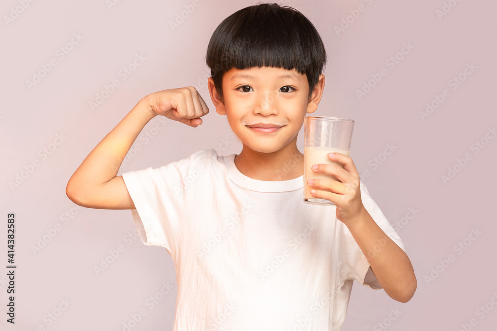 The Asian boy smiled happily, holding a glass of milk and acting like a muscular man. Asian pretty boy drinking the milk. The Asian boy smiled happily, holding a glass of milk and acting like a muscular man. Asian pretty boy drinking the milk.