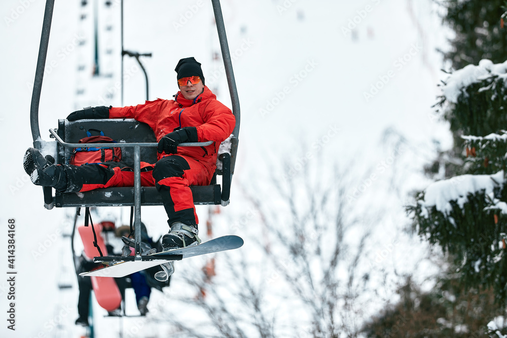 Skier sitting at ski lift in high mountains during sunny day. Winter sport and recreation, leisure outdoor activities.