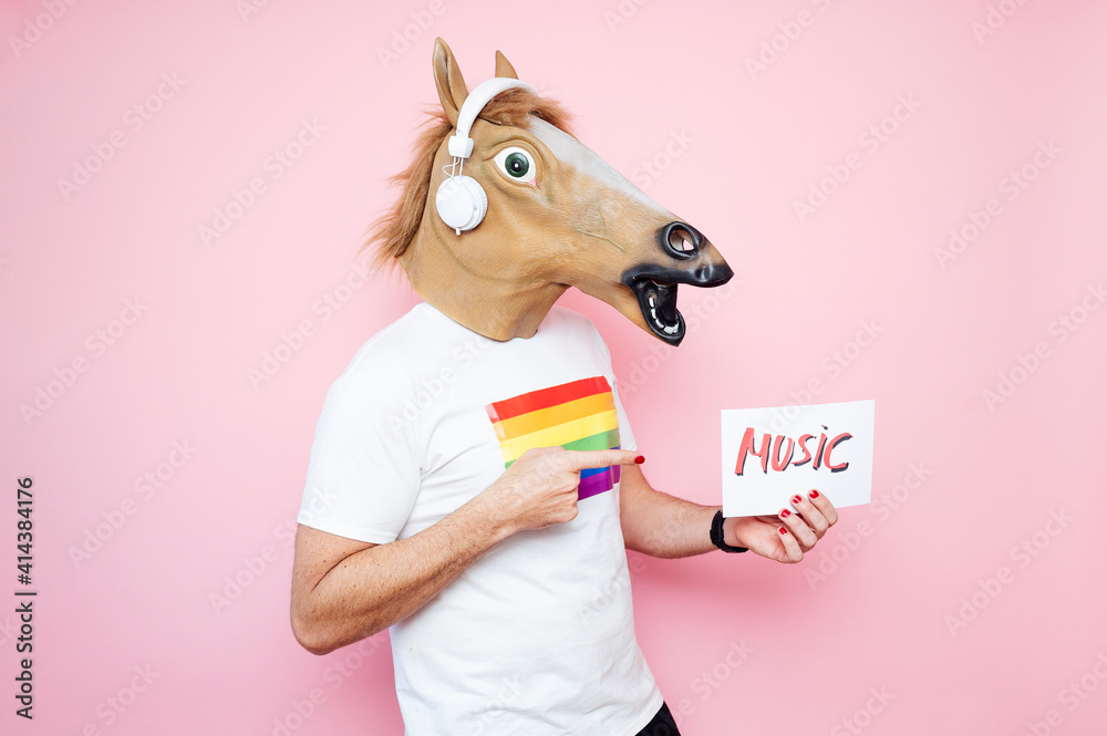 man in horse mask points to the sign that says 