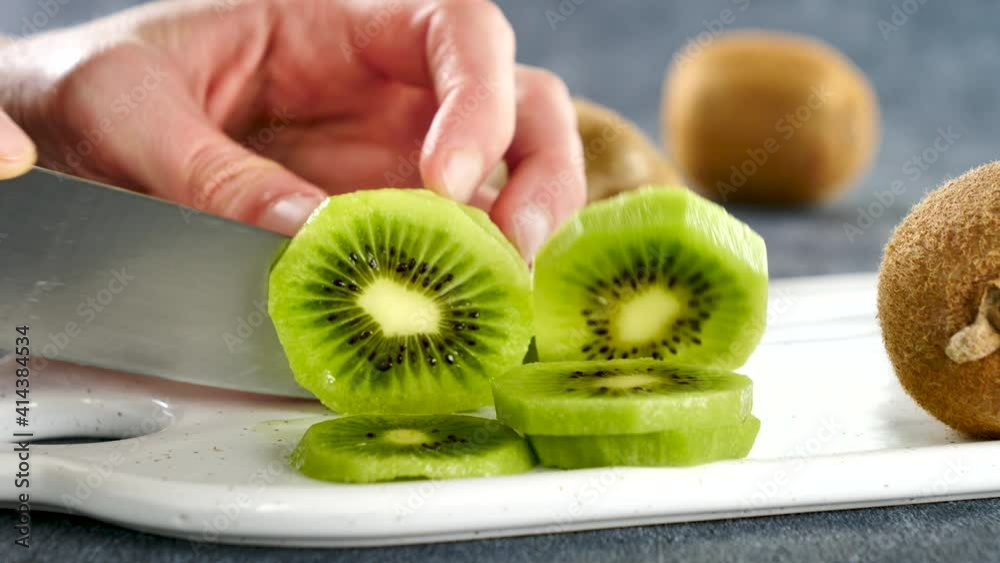 woman cutting fresh green kiwi