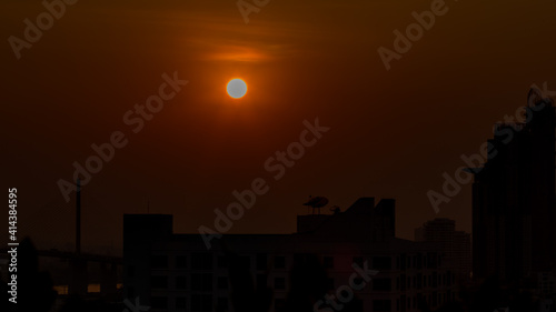 The blurred abstract background of the morning sun exposure to the tiny dust particles that surround the tall buildings in the capital, the long-term health issue of pollution © bangprik