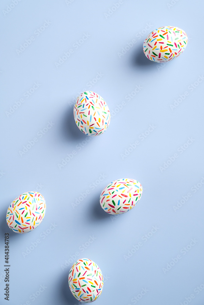 Happy Easter vertical banner. Colorful speckled Easter eggs on blue background. Flat lay, top view, minimal style.