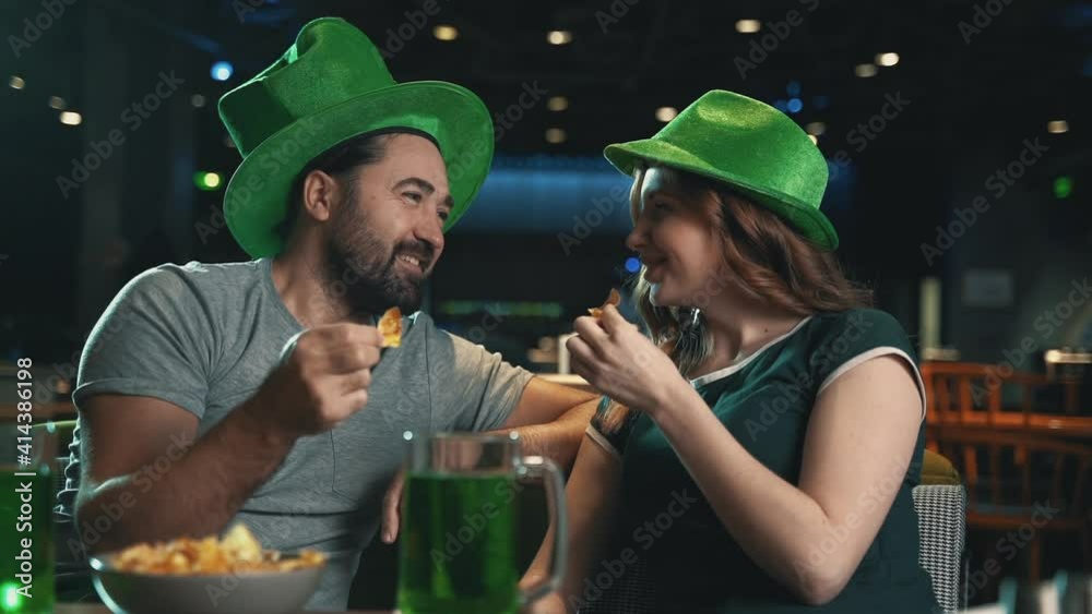 Celebrating Saint Patrick's Day in a pub. Man and woman in Irish hats eating. Celebrating Saint Patrick's Day in a pub. Man and woman in Irish hats eating.