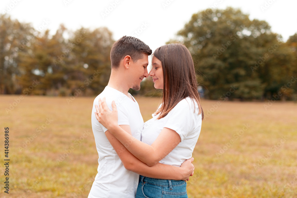 Cute lovely young couple embracing outdoor in park during sunset, romantic smiling people.