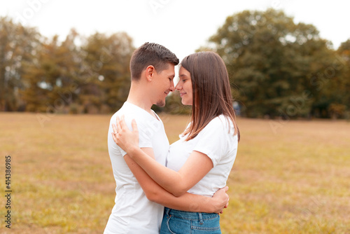 Cute lovely young couple embracing outdoor in park during sunset, romantic smiling people.