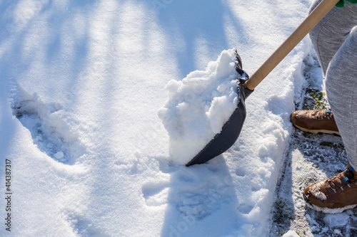 Child shoveling and removing snow in front of his house in the suburb