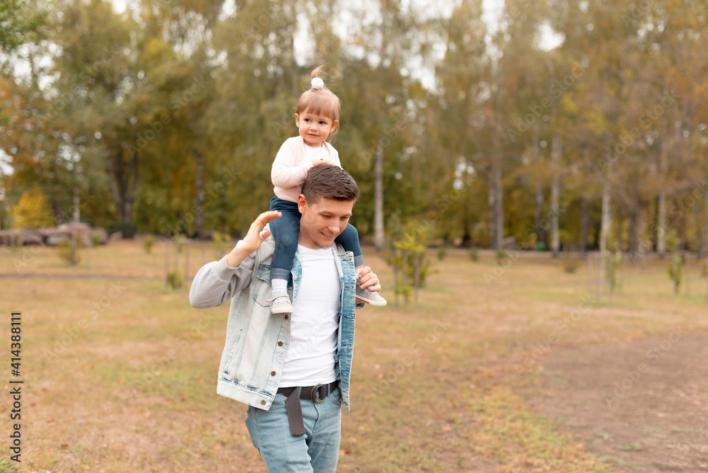 Fototapeta premium Happy young father on a walk with little daughter on his neck.
