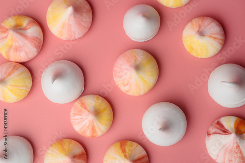 Colorful meringue cookies on pink background