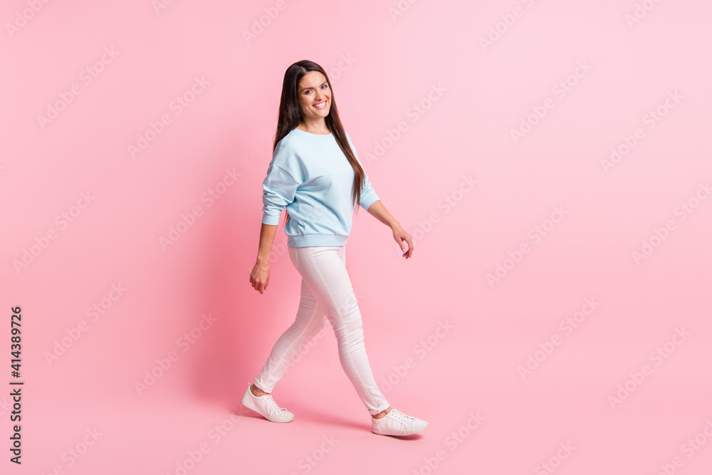 Full length body size photo of brunette long hair woman laughing stepping forward isolated on pastel pink color background Full length body size photo of brunette long hair woman laughing stepping forward isolated on pastel pink color background