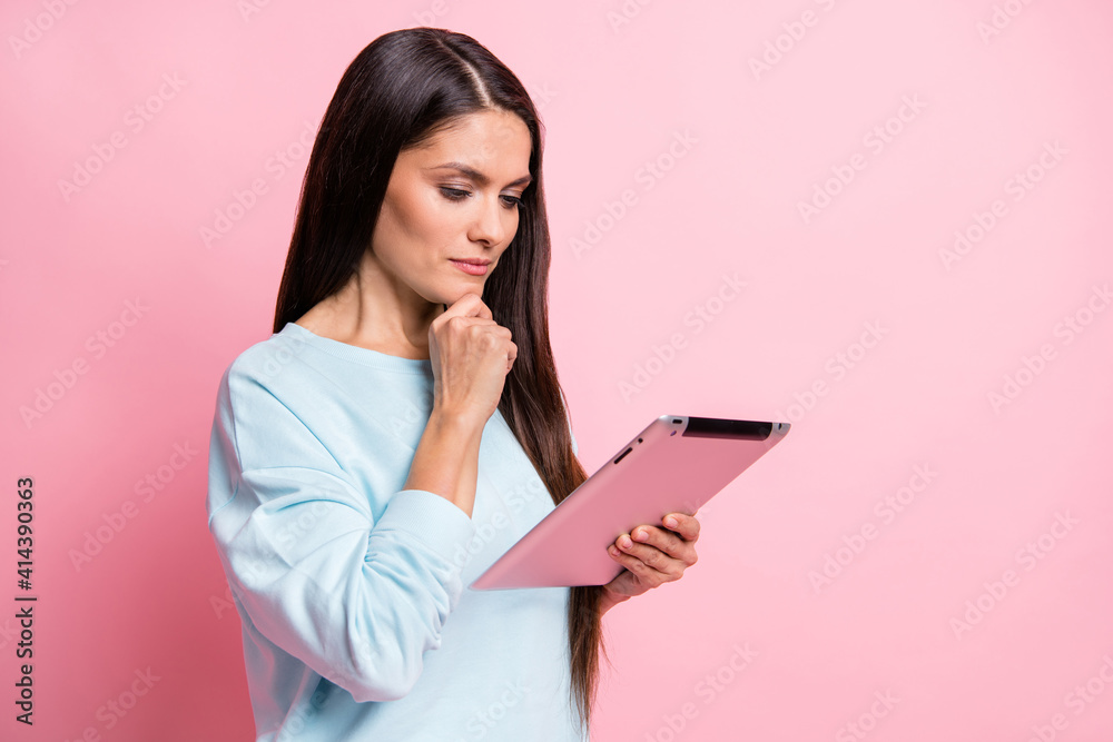 Photo portrait of thoughtful woman reading information on tablet focused smart isolated on pastel pink color background Photo portrait of thoughtful woman reading information on tablet focused smart isolated on pastel pink color background