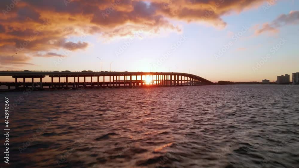 Aerial view low over the ocean towards traffic on the Biscayne Bay Bridge, sunset, in Miami - rising, drone shot Aerial view low over the ocean towards traffic on the Biscayne Bay Bridge, sunset, in Miami - rising, drone shot