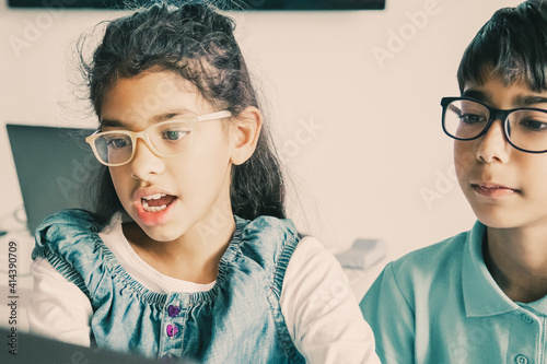 Foto Mixed-race little girl sitting at table and reading task aloud