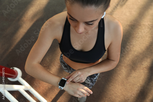 Woman using modern smart watch during training outdoors, top view