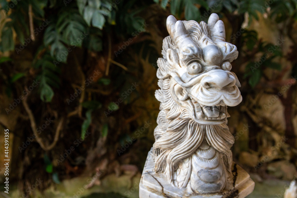 Dragon stone carved statue on green garden background. Chinese zodiac animal sculpture. Marble dragon statue