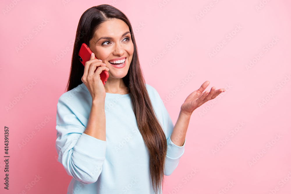 Photo portrait of brunette talking on mobile phone gesturing hands looking at empty space isolated on pastel pink color background Photo portrait of brunette talking on mobile phone gesturing hands looking at empty space isolated on pastel pink color background
