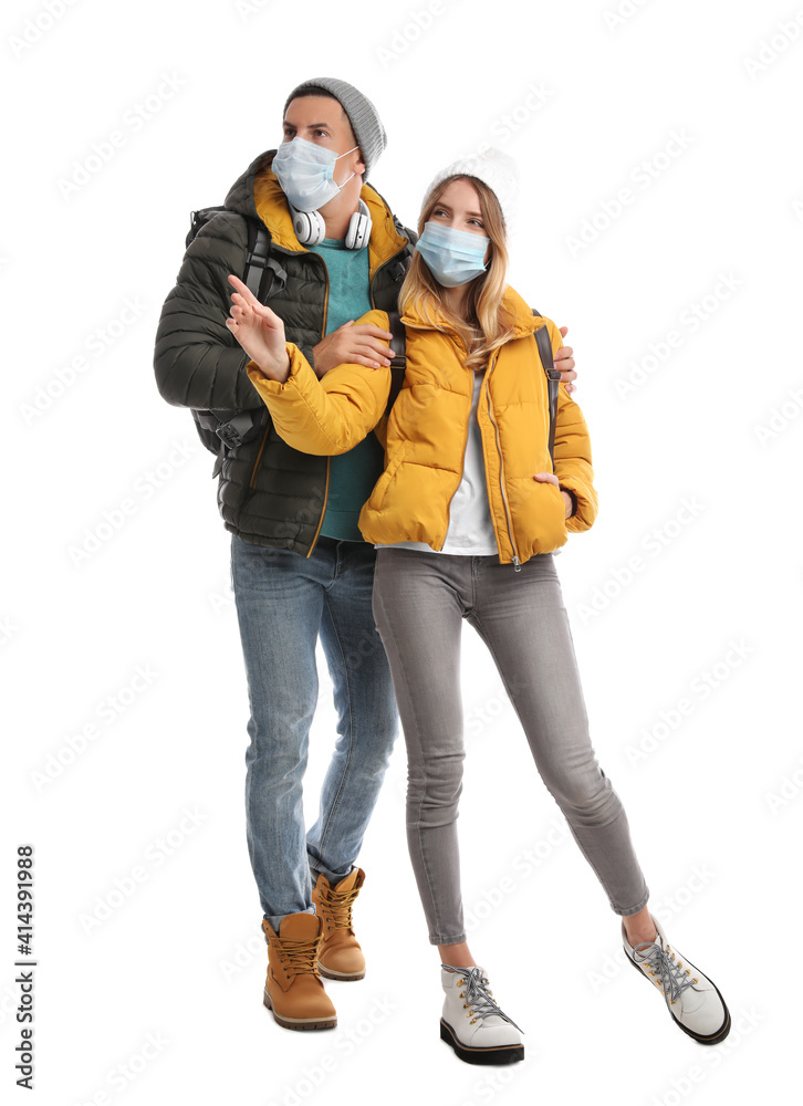 Couple in face masks and warm clothes on white background. Winter travel Couple in face masks and warm clothes on white background. Winter travel