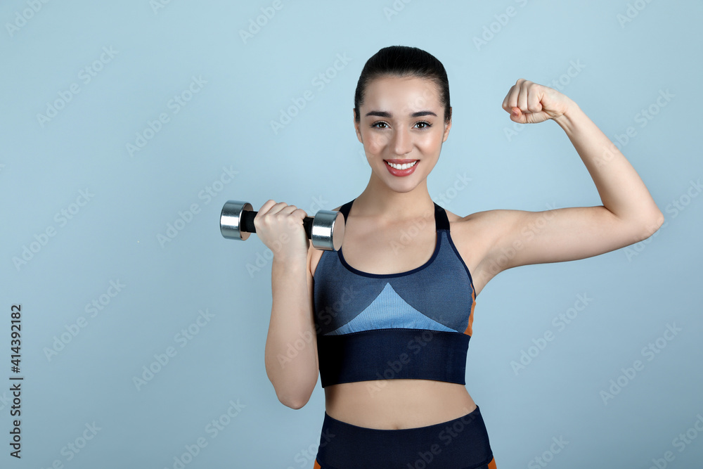 Woman with dumbbell as girl power symbol on light grey background. 8 March concept Woman with dumbbell as girl power symbol on light grey background. 8 March concept