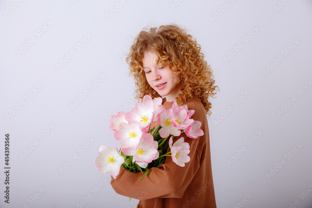 curly haired teen girl hold  bouquet of spring pink tulips on a white background