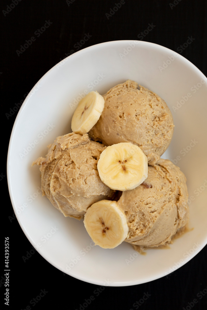 Homemade Peanut Butter Banana Ice Cream in a Bowl on a black background, top view. Flat lay, overhead, from above. Close-up. Homemade Peanut Butter Banana Ice Cream in a Bowl on a black background, top view. Flat lay, overhead, from above. Close-up.