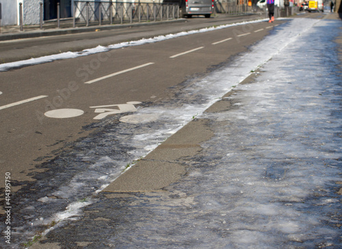 far away jogger running on partly frozen city bicycle lanes