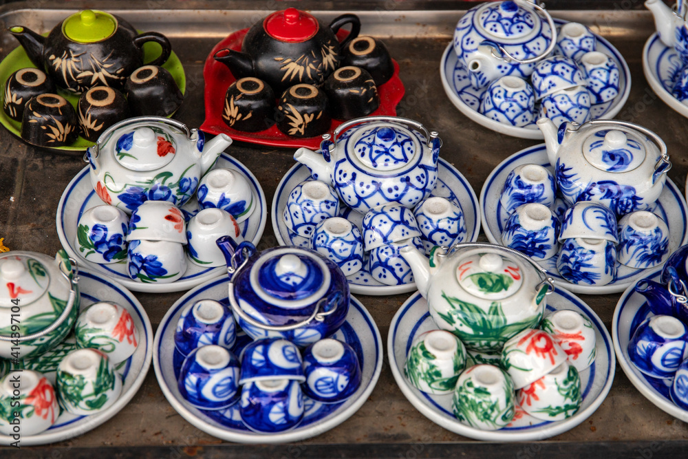 Small tea sets for sale on tourist market. Ceramic tea pot and cup with handmade ornament. Vietnamese porcelain