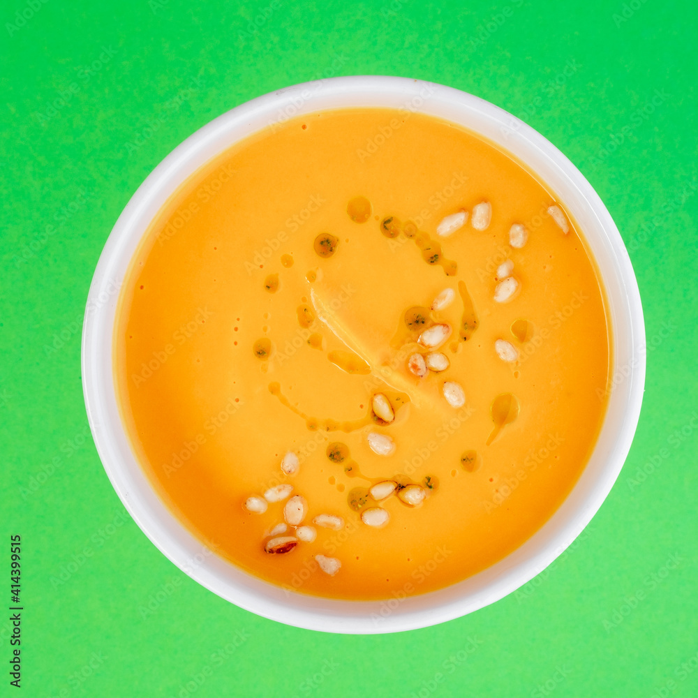 Pumpkin soup in white plate on green background. Close-up. Top view. Space for text. Photo for cutting, for menu Pumpkin soup in white plate on green background. Close-up. Top view. Space for text. Photo for cutting, for menu
