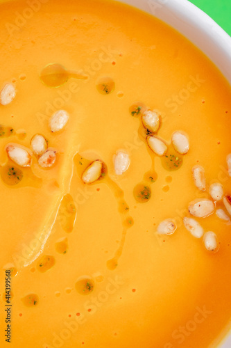 Pumpkin soup in a white plate on a green background. Close-up. Photo for clipping, for the menu