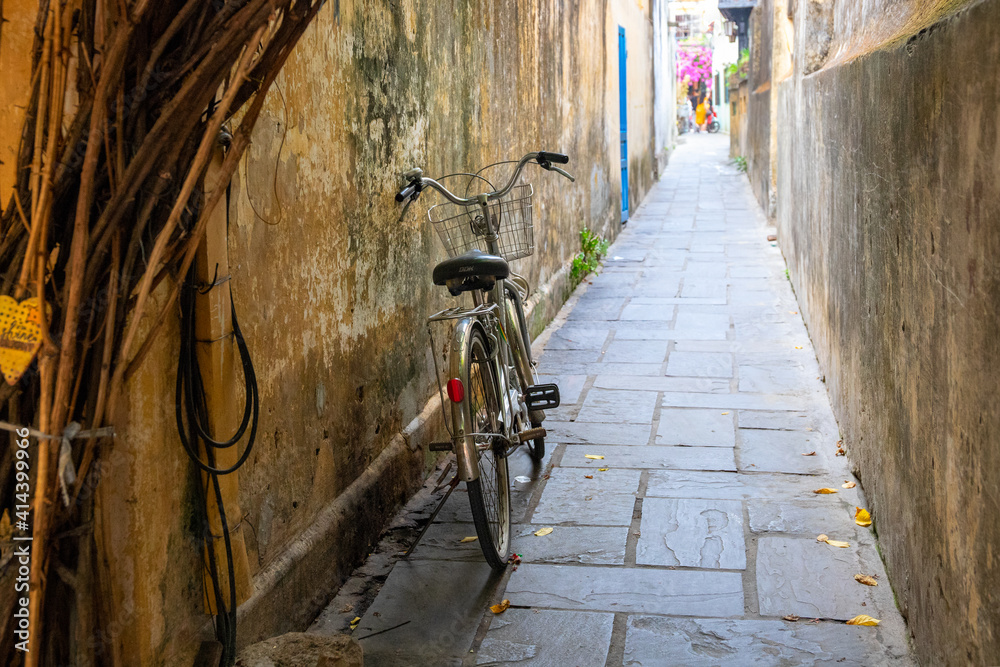 Narrow street of asian town with electric wire and bicycle. Vietnam culture and travel. Old bike on tiny street.