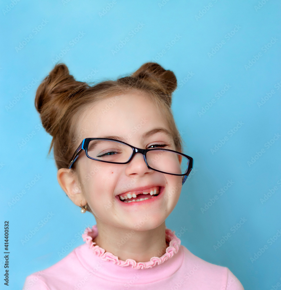 portrait of a laughing girl child with glasses on a blue background portrait of a laughing girl child with glasses on a blue background