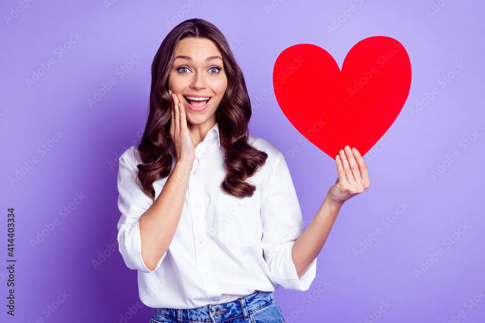 Photo of adorable lady hold heart shape card palm cheek open mouth wear white shirt isolated purple color background
