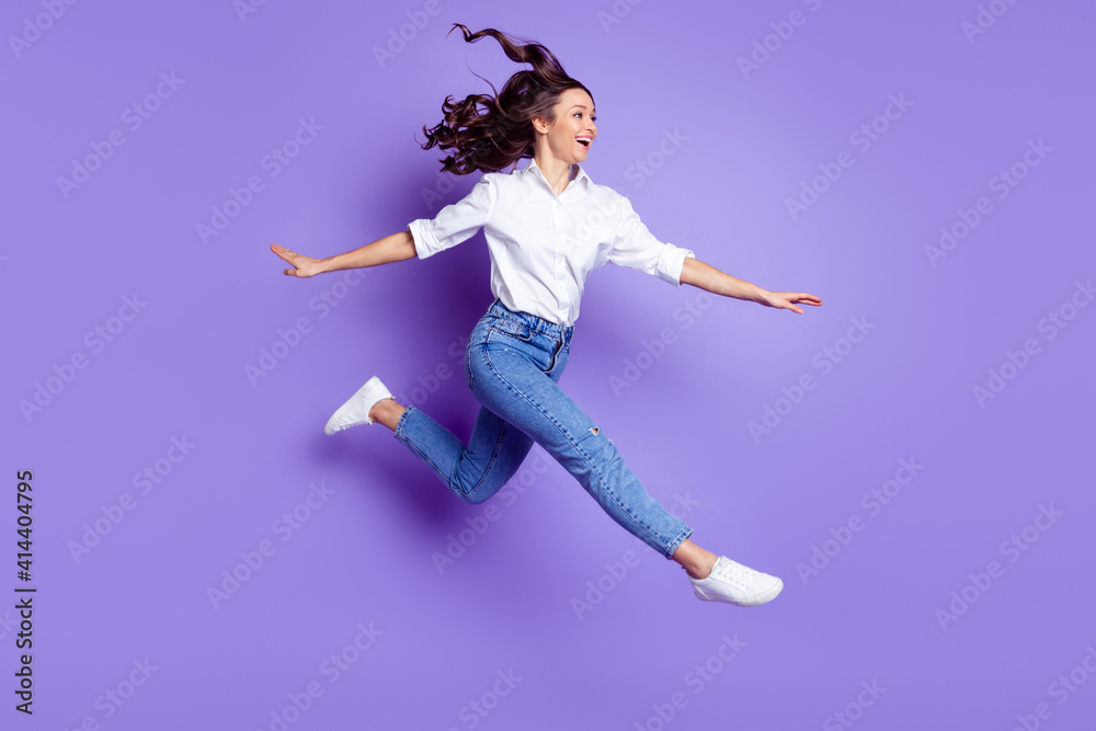 Profile photo of sporty lady jump run look empty space wear white shirt jeans shoes isolated purple color background