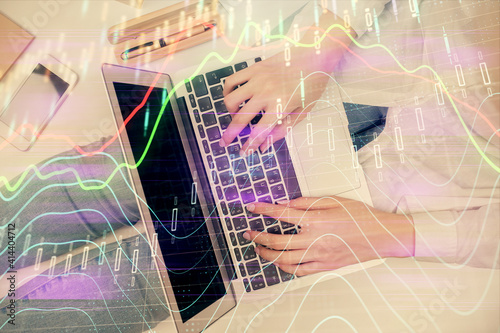 Double exposure of woman hands working on computer and forex graph hologram drawing. Top View. Financial analysis concept.