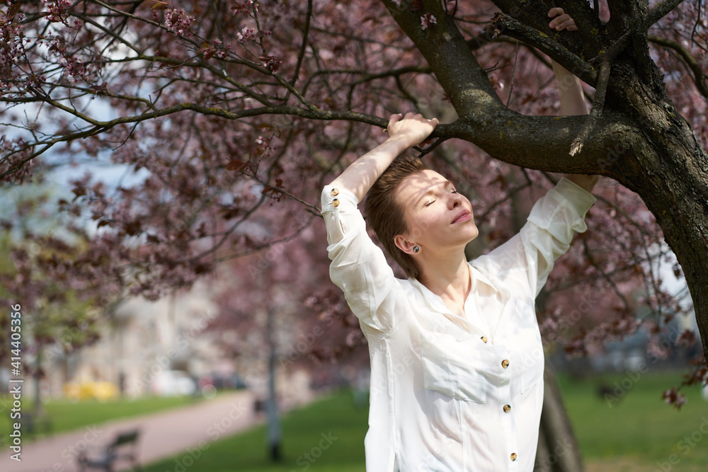 Young tranquil pretty woman with closed eyes on the background of blooming sakura. Young tranquil pretty woman with closed eyes on the background of blooming sakura.