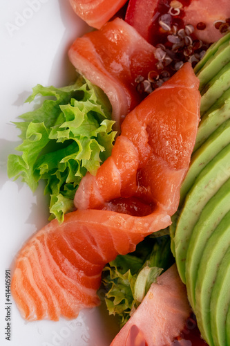 Salad with quinoa, salmon, avocado, tomatoes, lettuce and Philadelphia cheese in a white plate close up