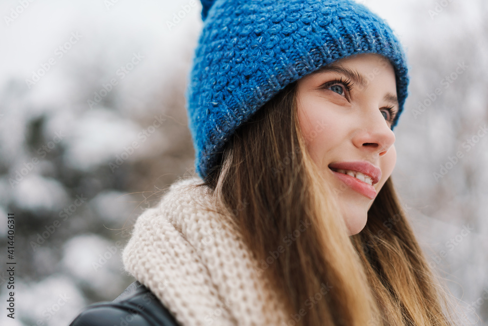 Happy beautiful girl in knit hat smiling while walking in winter park Happy beautiful girl in knit hat smiling while walking in winter park