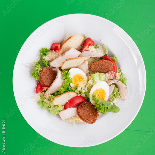 Caesar salad on a white plate on a green background. close-up. photo for clipping. for the menu