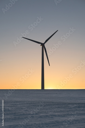 backlit wind turbine at sunset