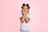 African American black child girl smiling and looking at camera on pink background, standing leaning her face on hands