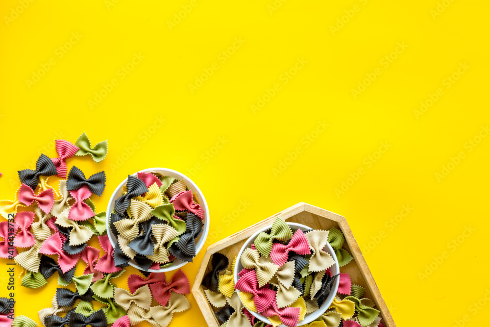 Italian farfalle pasta in bowls. Raw multicolored farfalle pasta, overhead view