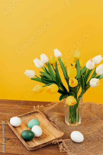 easter eggs on a wooden tray a bouquet of flowers spring holiday easter yellow background