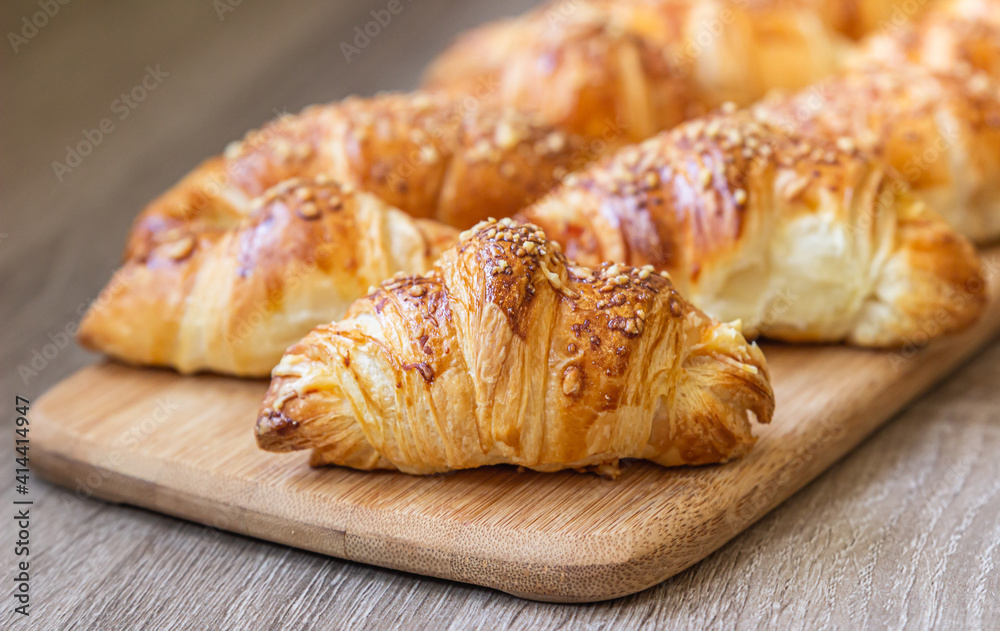 Homemade croissants with cheese on wooden board. Baking for breakfast.