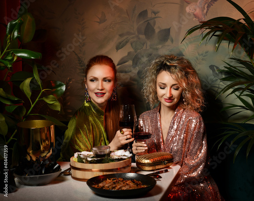Fényképezés Two rich gorgeous women friends wearing fashionable dresses are having good time