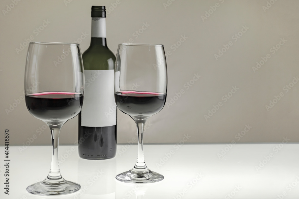 Two large glasses with red wine and a bottle on a blurred background, close-up. Horizontal photo Two large glasses with red wine and a bottle on a blurred background, close-up. Horizontal photo