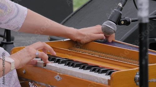 Slow motion: woman hands playing ethnic Indian classical harmonium keyboard on stage of summer open air concert - close up view. Entertainment, music, culture, leisure time and art concept photo